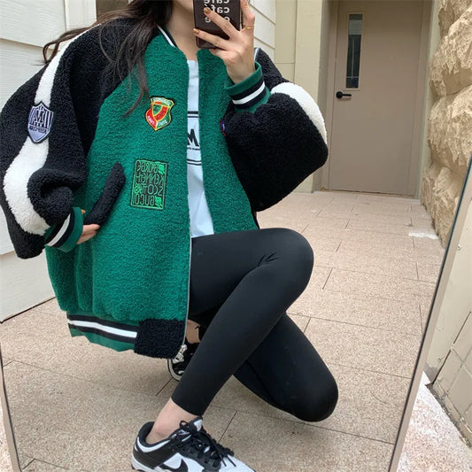 Person wearing a green varsity jacket with patches, sitting on a step.