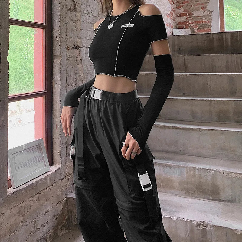 Person wearing a black outfit with long sleeves and cargo pants in an urban setting.